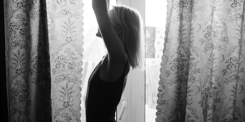 Silhouette of a person in a flowing yoga pose against a window.